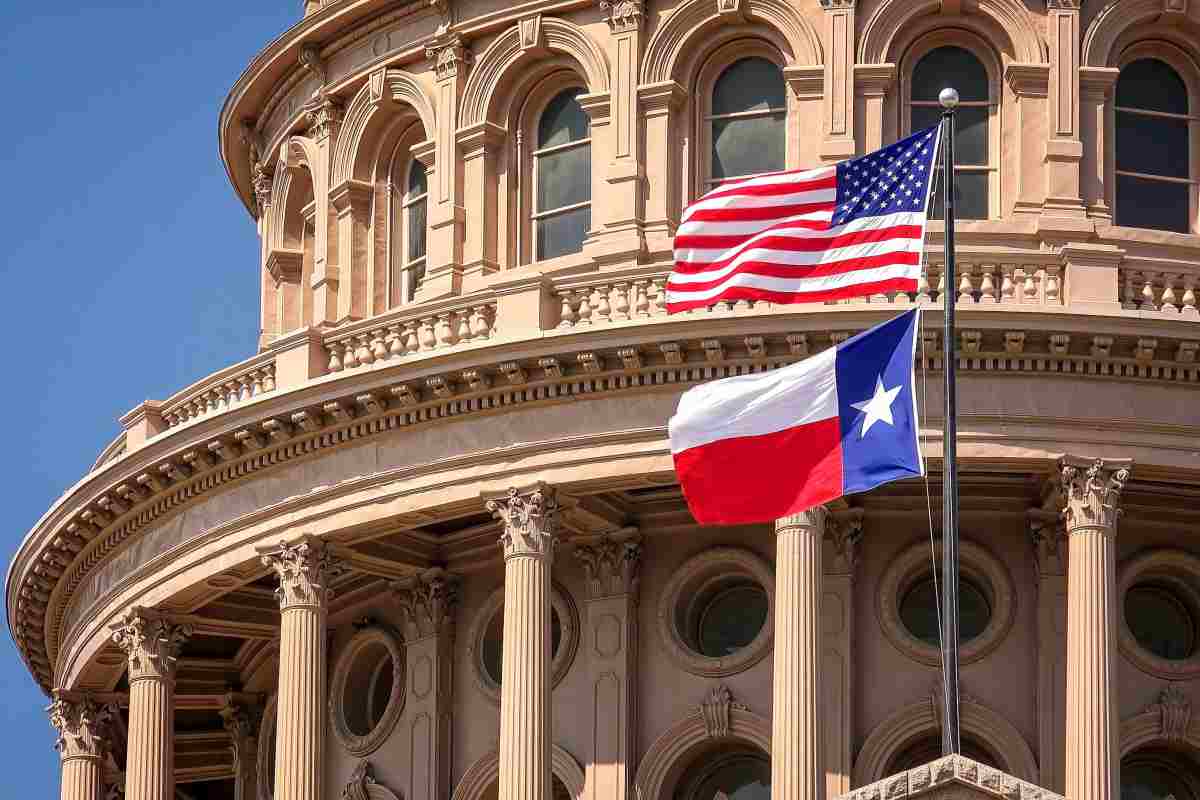 American and Texas state flags flying on the dome of the Texas State Capitol building in Austin