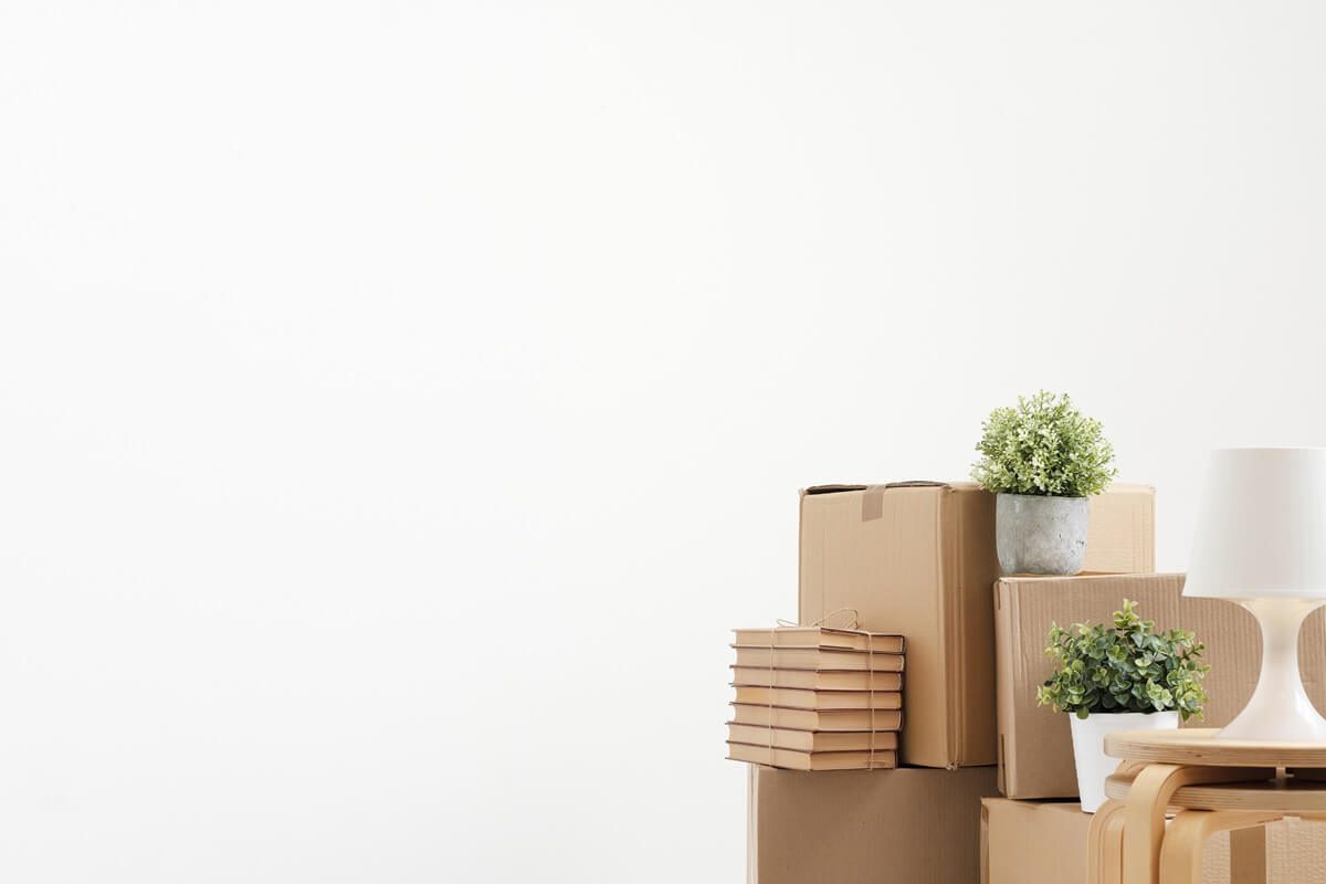 cardboard boxes of things are stacked on the floor against a white wall