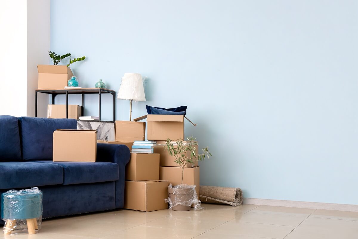 cardboard boxes with belongings and sofa in new flat on moving day