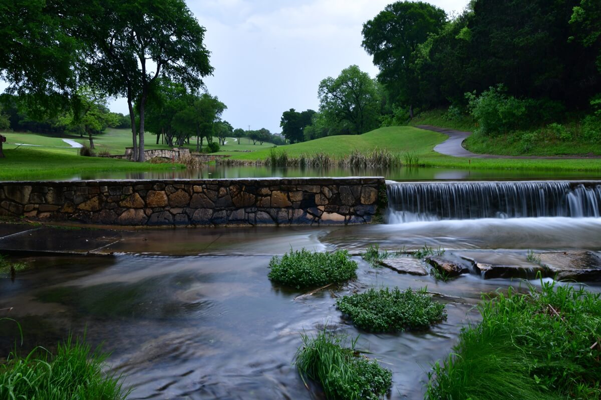 gold course cart path crossing a small stream late in the evening after a rain shower in Leander TX