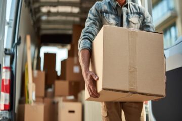 housing moving checklist planning concept. delivery person carrying a box from a van filled with packages