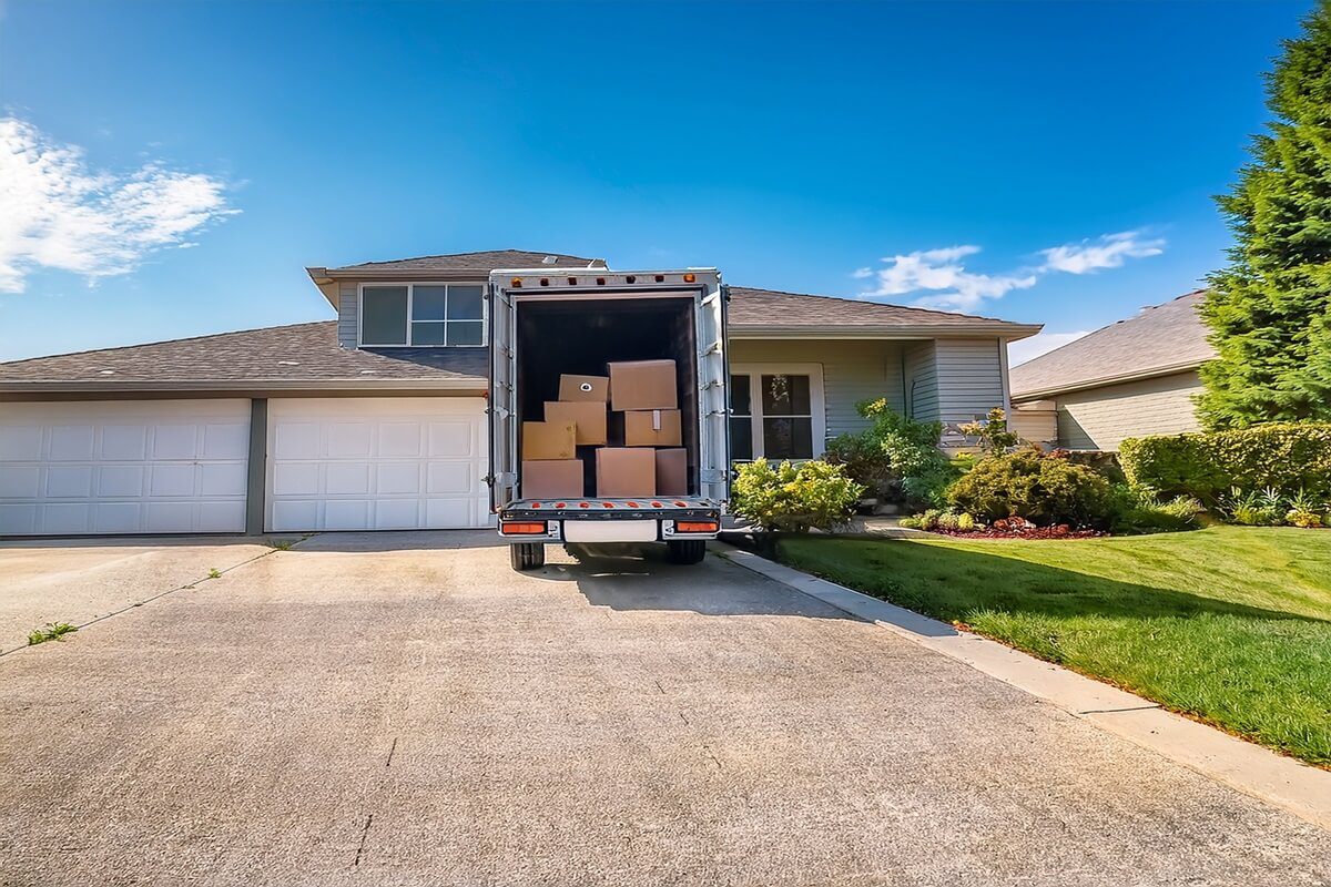 open moving truck in driveway of upscale suburban house wide banner