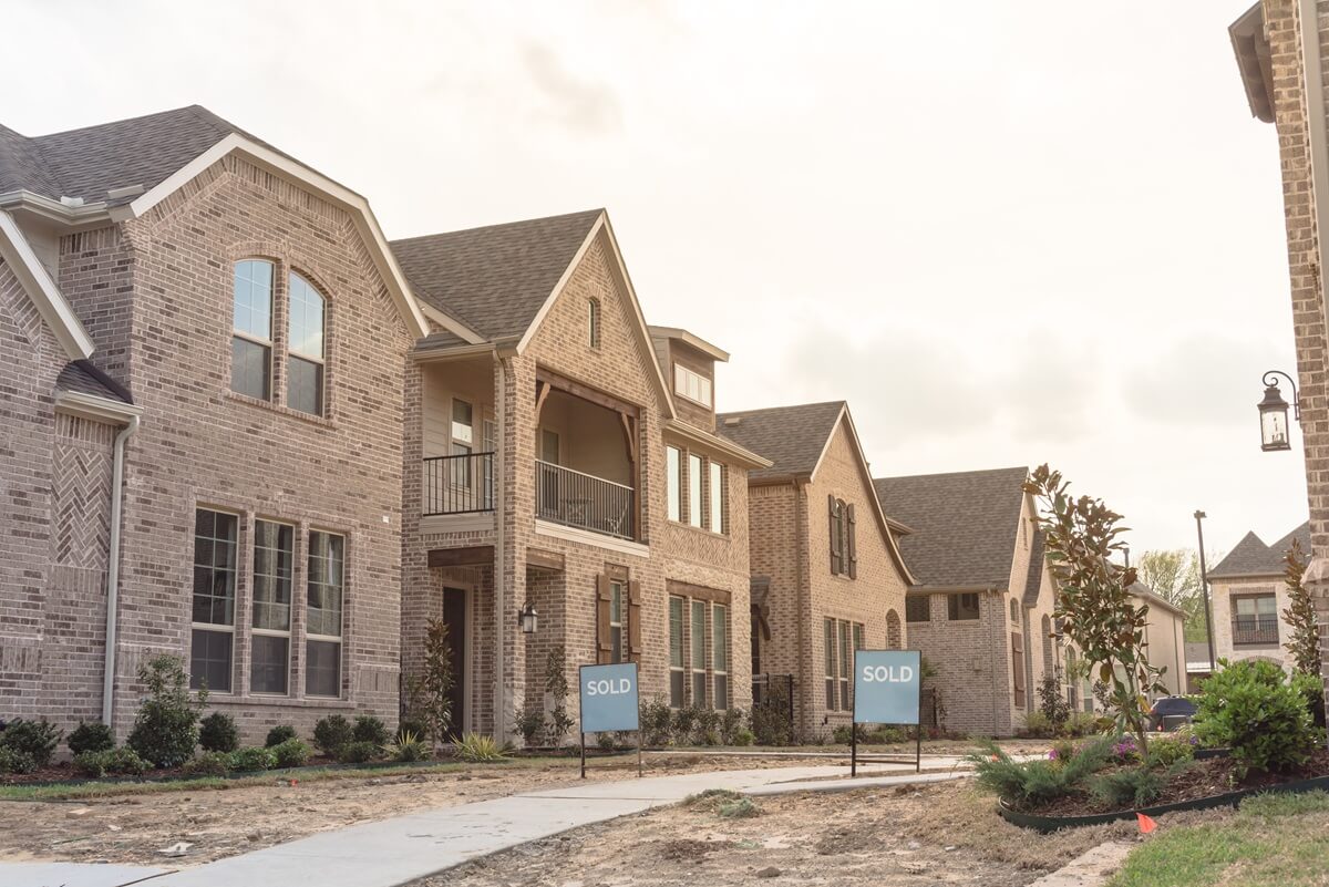 row of newly built detached single-family homes and sold out sign