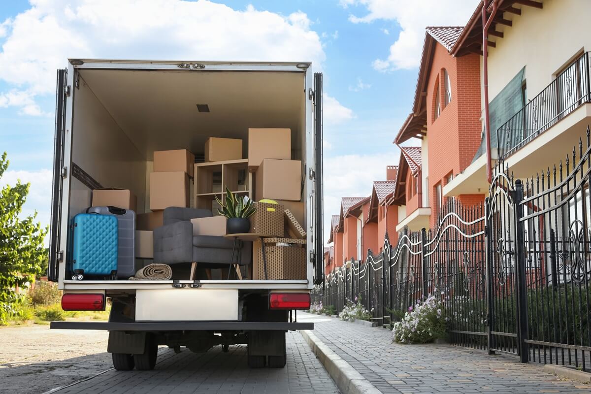 van full of moving boxes and furniture near house